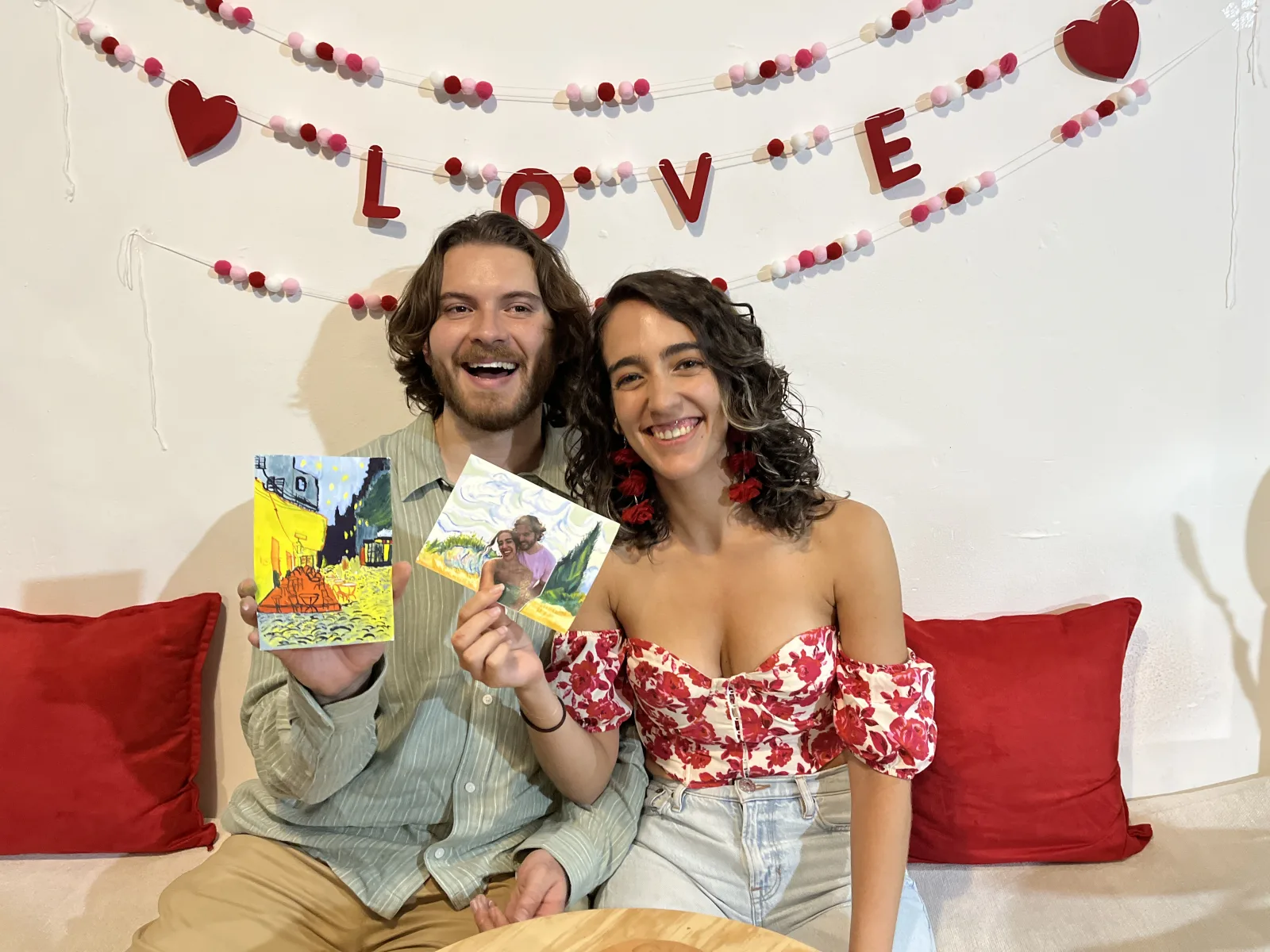 Una pareja muestra sus pinturas en gouache bajo un letrero de LOVE en un taller para San Valentín